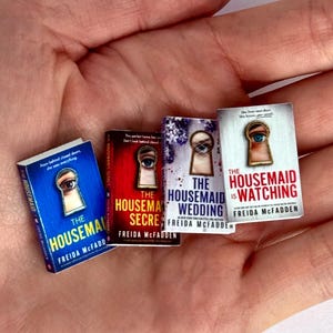 May include: A set of miniature books with the titles "The Housemaid," "The Housemaid's Secret," "The Housemaid's Wedding," and "The Housemaid is Watching" by Freida McFadden. Each book has a keyhole design and a different colour scheme.