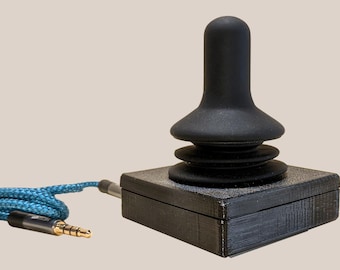 May include: A black joystick with a blue cable. The joystick has a round, black top and a square base.