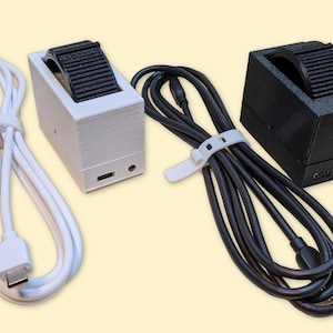 May include: Two 3D printed watch chargers, one white and one black, with their respective USB cables.