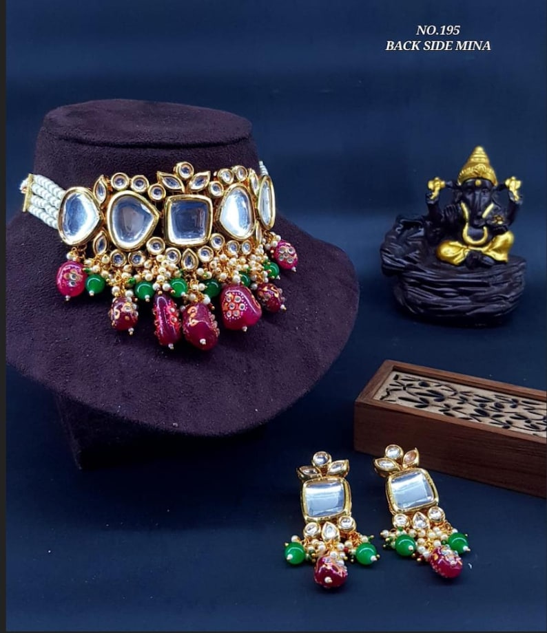 May include: A gold choker necklace with a pearl and mirror design. The necklace has a red and green beaded tassel. Matching earrings with a similar design are also included. The image text reads "NO.195 BACK SIDE MINA".