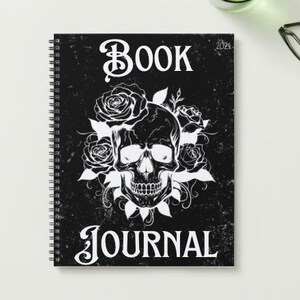 May include: Black and white journal cover with a skull and roses design. The text "BOOK JOURNAL" is printed on the cover.