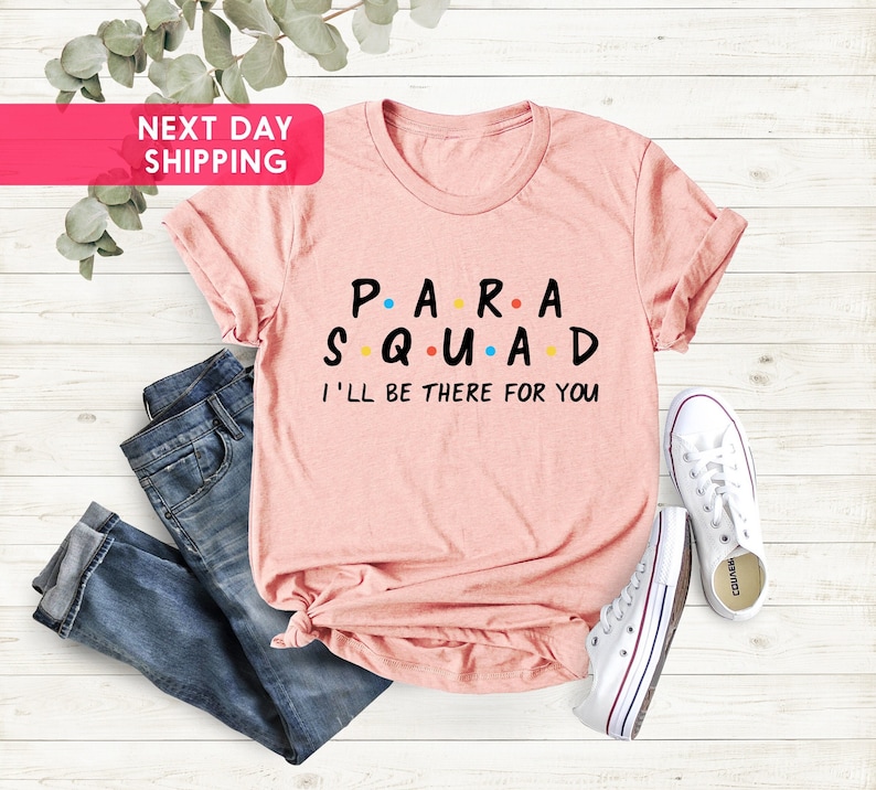 May include: A pink t-shirt with the text "P.A.R.A.S.Q.U.A.D I'LL BE THERE FOR YOU" in black letters with colorful dots.