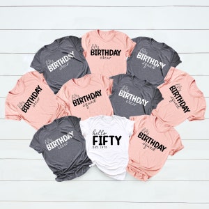 May include: A set of eight t-shirts with different designs celebrating a 50th birthday. The shirts are in gray and pink with black text. One shirt says "hello fifty est. 1973".