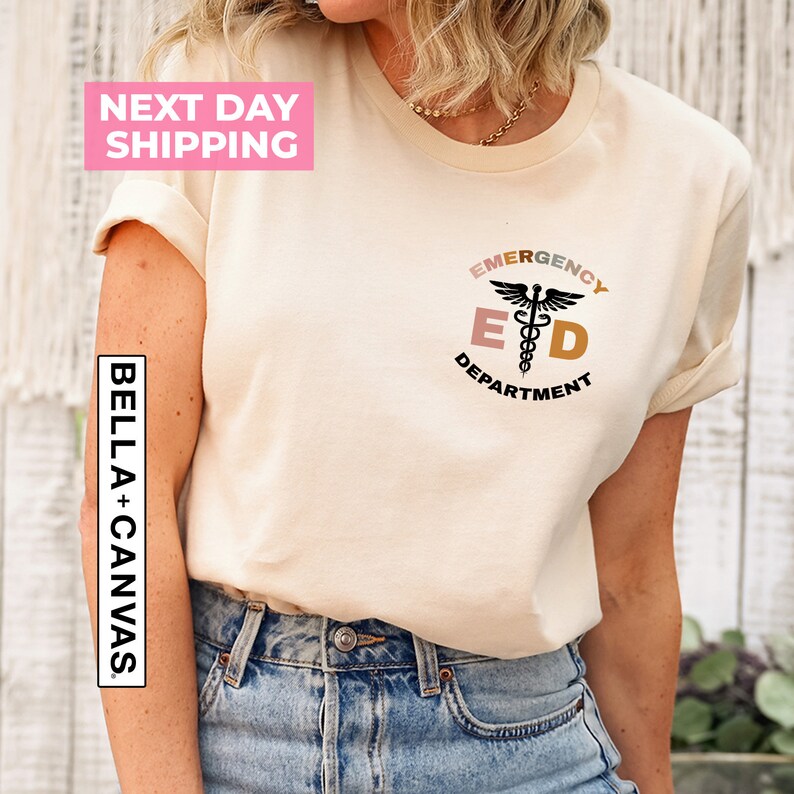May include: A beige t-shirt with a black graphic of a medical symbol and the text "Emergency Department" in a circle with a pink, orange, and yellow color scheme.
