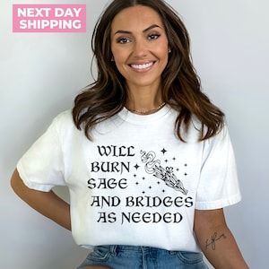 Puede incluir: Camiseta blanca con texto negro que dice "Will burn sage and bridges as needed" con una peque&ntilde;a ilustraci&oacute;n de un manojo de salvia ardiente.
