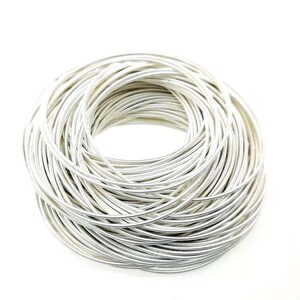 May include: A close-up of a bundle of silver-colored wire, coiled into a circular shape.