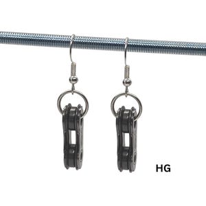 Peut inclure: Une paire de boucles d'oreilles en chaîne de vélo gris foncé. Chaque boucle d'oreille est composée d'une petite section de chaîne de vélo suspendue à un crochet argenté. Les boucles d'oreilles sont suspendues à une tige métallique argentée. Les lettres "HG" sont visibles.