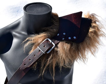 May include: A brown leather shoulder armor with a fur trim and a silver buckle. The armor is worn on a black mannequin.