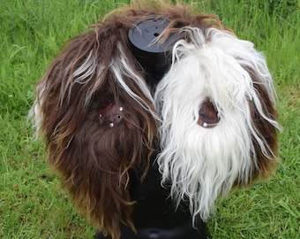 May include: A brown and white sheepskin vest with leather accents and metal rivets. The vest is displayed on a black mannequin.