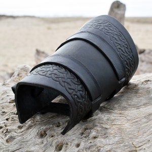 Schwarze Wikinger Armschiene mit geprägtem Knoten Muster und zwei Leder Riemen.