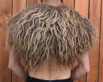 May include: A brown and blonde faux fur shawl with a shaggy texture. The shawl is worn by a person with their back to the camera.