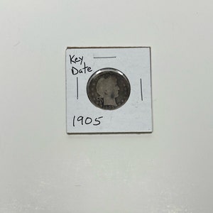 May include: A silver 1905 US quarter coin with the words "Key Date" written on a white card.