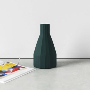 May include: A dark green ceramic vase with a fluted design. The vase has a narrow neck and a wide base.