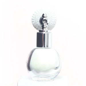 May include: A silver atomizer bottle with a clear glass body and a silver cap. The bottle has a textured, iridescent finish.