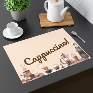 May include: A beige placemat with the word "Cappuccino!" in brown script. The placemat features watercolor illustrations of coffee-making equipment and coffee drinks, including a French press and a barista.