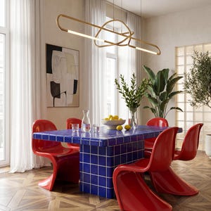 May include: A contemporary dining space with a blue tiled table and red chairs. A gold light fitting hangs above the table, and a vase of flowers and a bowl of lemons sit on the table. The room has wooden flooring and large windows.