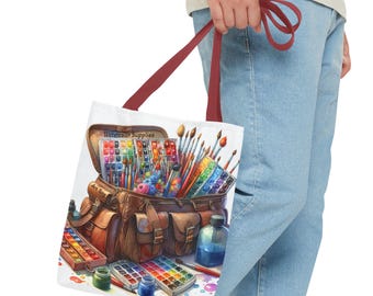 Peut inclure: Un sac fourre-tout blanc avec une poignée rouge. Le sac est rempli de fournitures de peinture à l'eau, y compris des tubes de peinture, des pinceaux et des palettes. Le sac porte l'inscription "Watercolor Supplies".