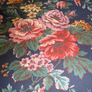 May include: A navy blue fabric with a floral pattern featuring pink, red, and yellow flowers. The fabric has a textured surface.
