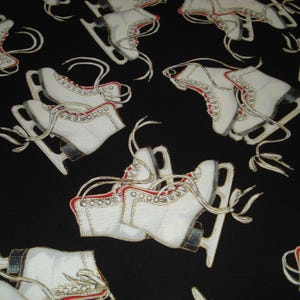 May include: Black fabric with a repeating pattern of white ice skates. The skates have red accents and laces, with silver blades. The design is a classic winter sports theme.