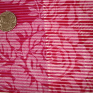 May include: Close-up of a fabric with a floral pattern in shades of red and pink, overlaid with white horizontal stripes. A U.S. quarter coin is placed on the fabric for scale.