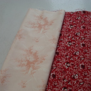 May include: Two fabric swatches, one with a pale pink background and a white floral pattern, and the other with a red background and a white floral pattern.