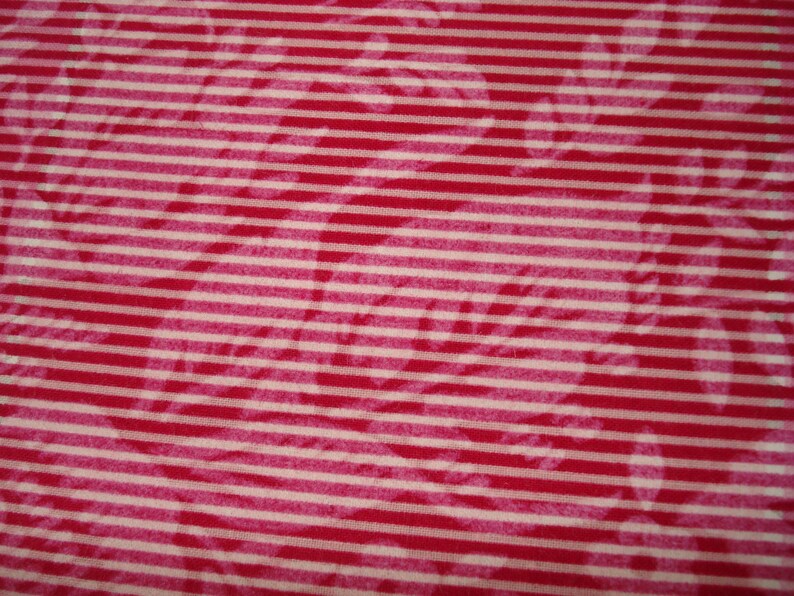 May include: A close-up shot of a fabric featuring a red and white striped design. The stripes run horizontally across the material. Subtle floral patterns are also visible, adding a delicate touch to the overall design.