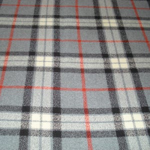 May include: Close-up of a gray plaid fabric with a repeating pattern of black, red, and white lines. The fabric has a soft, textured appearance, suitable for apparel or home decor projects.