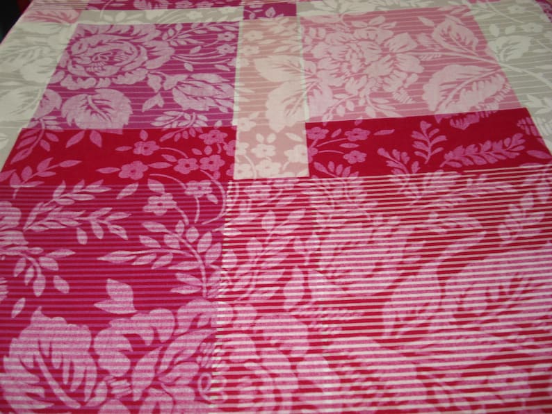 May include: A patchwork quilt with floral designs in pink, red, and white. The quilt features large roses, small flowers, and striped details. The design combines various textures and patterns, creating a visually appealing textile.