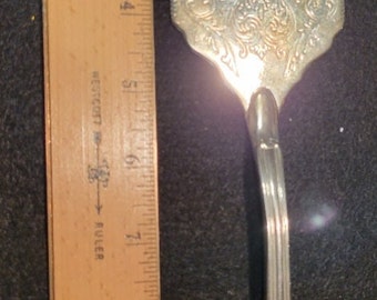 Decorative silver serving piece.  Perhaps for serving cake.  Or.... Silver Fly Swatter (not really).