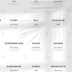 May include: A white background with a shadow of palm leaves.  The image shows nine labels with the names of herbs and spices, including Curry, Dill, Estragon, Gewürznelken, Honig, Ingwer, Kardamom, Kerbel, and Knoblauch. Each label includes the word "Herb" or "Seasoning" and "All Natural".