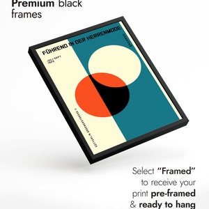 May include: A black framed print with a geometric design featuring overlapping circles in red, white, and black on a teal background. The text "F&Uuml;HREND IN DER HERRENMODE" is printed in white at the top of the print. The text "JULI-SEPT 1923" is printed in white below the title. The text "SOTTERLIN BROENERSTRASSE II" is printed in white at the bottom of the print. The text "BAUHAUS" is printed in white at the bottom right corner of the print.