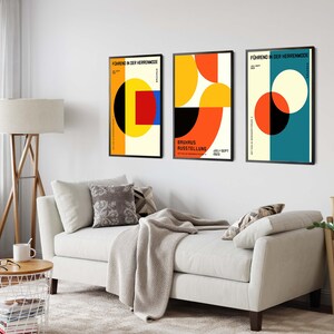 May include: Three minimalist geometric posters with black frames. The posters feature abstract shapes in red, yellow, blue, and black on a white background. The text on the posters reads "F&uuml;hrung in der Heitermode" and "Europ&auml;ische Ausstellung".