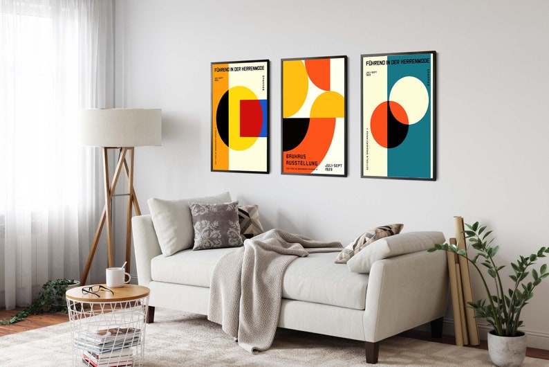 May include: Three minimalist geometric posters with black frames. The posters feature abstract shapes in red, yellow, blue, and black on a white background. The text on the posters reads "F&uuml;hrung in der Heitermode" and "Europ&auml;ische Ausstellung".