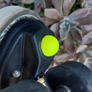 small jam plug close up picture,in yellow,; a plant is seen on the background mounted on a black roller skate