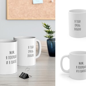 May include: Two white ceramic mugs with black text. One mug says "MAM. I ate and in a hat." The other mug says "I love you very much".