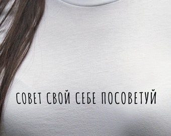 以下が含まれることがあります： 黒い文字で「совет свой себе посоветуй」とプリントされた白いTシャツです。