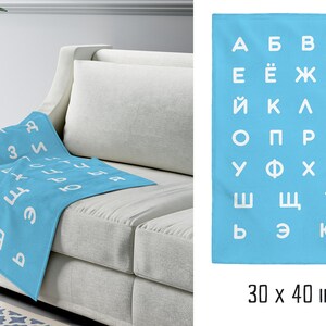 May include: A light blue throw blanket with a white Cyrillic alphabet pattern. The blanket is 30 x 40 inches.