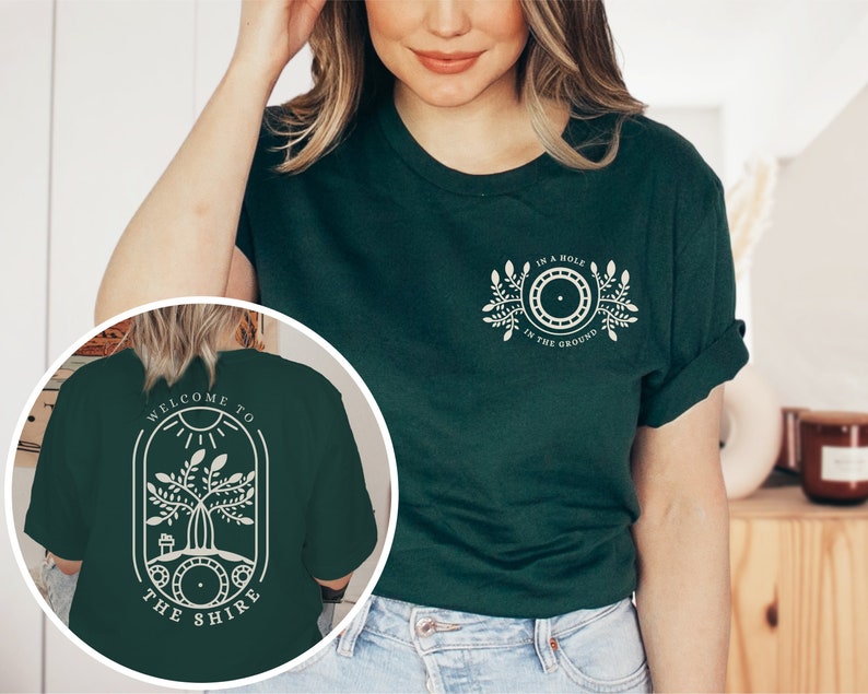 May include: A dark green t-shirt with a white graphic on the front that says "In a hole in the ground" and a white graphic on the back that says "Welcome to the Shire".