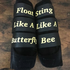 May include: Pair of black horse leg wraps with yellow text that reads "Float Like A Butterfly" and "Sting Like A Bee".