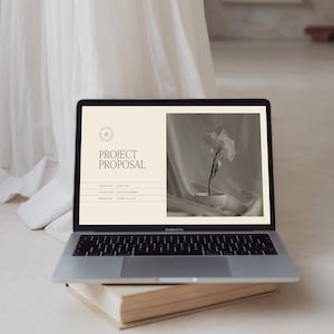 Peut inclure: Un ordinateur portable ouvert sur un document de proposition de projet. Le document a un design simple avec une photo en noir et blanc d'une fleur dans un bol blanc. Le texte sur le document indique "Proposition de projet".