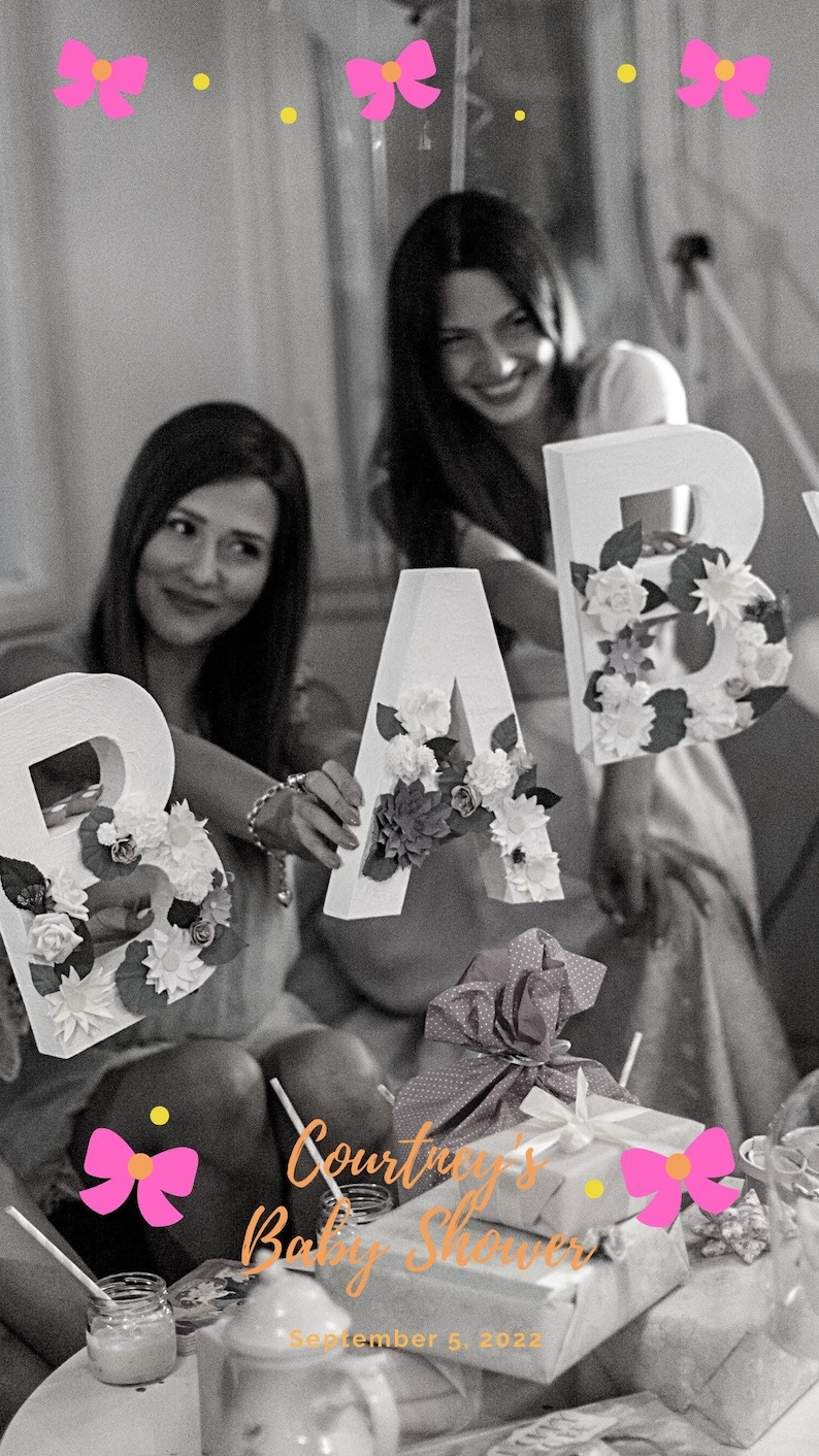 Puede incluir: Dos personas sosteniendo grandes letras blancas que deletrean "BABY" decoradas con flores blancas. Las letras est&aacute;n frente a un fondo en blanco y negro. El texto "Courtney's Baby Shower September 5, 2022" est&aacute; en la parte inferior de la imagen.
