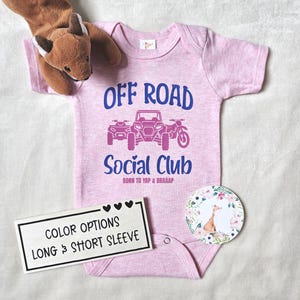 Könnte beinhalten: Ein hellrosa Baby-Body mit dem Text "OFF ROAD Social Club" und Illustrationen eines ATVs, eines Side-by-Side-Fahrzeugs und eines Motorrads. Der Body hat auch den Text "BORN TO YAP & BRAAAP". Ein Schild lautet "COLOR OPTIONS LONG & SHORT SLEEVE".
