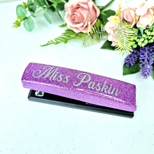 May include: Purple glitter stapler with the name "Miss Paskin" engraved on the top.