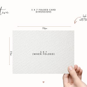 May include: A white, textured 5 x 7 inch folded card is held by a hand. The dimensions are displayed, with the card measuring 7 inches wide and 5 inches high when folded. Text on the card reads "5 X 7 (WHEN FOLDED)".