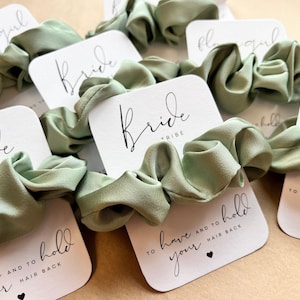 Peut inclure: Ensemble de chouchous en satin vert avec des cartes blanches qui disent "Bride Tribe" et "To have and to hold your hair back".