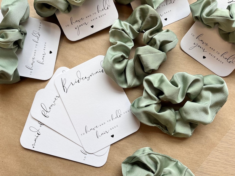 Peut inclure: Ensemble de quatre chouchous en satin vert avec des cartes blanches qui disent "To have and to hold your hair back" et "Bridesmaid" et "Maid of Honor" et "Flower Girl".