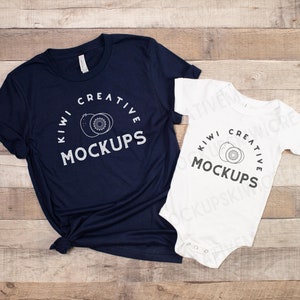 May include: Two t-shirts with the text "Kiwi Creative Mockups" and a graphic of two kiwi fruit slices. The larger t-shirt is navy blue and the smaller t-shirt is white.