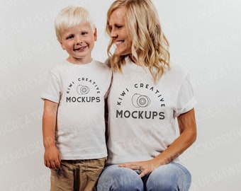 May include: A white t-shirt with a black kiwi fruit graphic and the text "Kiwi Creative Mockups". A child and an adult are wearing the shirts.