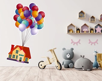 May include: A yellow house with red trim is lifted into the air by a bunch of colorful balloons. The house has two windows and a door. The balloons are red, orange, yellow, green, blue, and purple. The house is floating in front of a white wall with wooden shelves and decorations.