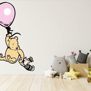 Puede incluir: Winnie de Pooh y Piglet sujetando un globo rosa. Los personajes est&aacute;n en un estilo de dibujos animados y sujetan una cuerda atada al globo. El fondo es una pared blanca con un suelo de madera.